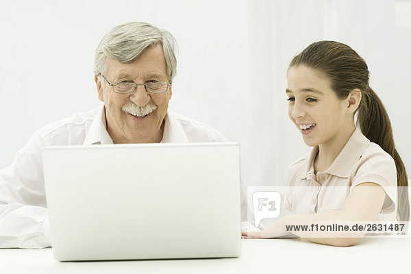 Grandfather and granddaughter looking at laptop together