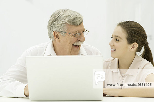 Grandfather and granddaughter sitting with laptop  laughing