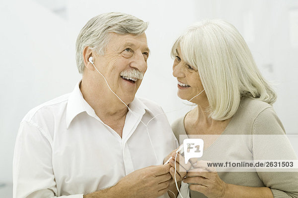 Seniorenpaar beim gemeinsamen Hören des MP3-Players