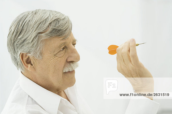 Älterer Mann mit Dartpfeil  zielend