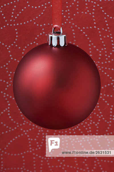 Red Christmas tree ornament hanging from red ribbon