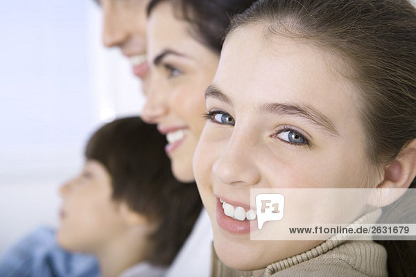 Girl sitting with family  smiling at camera  close-up