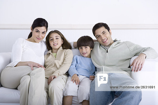 Familie mit zwei Kindern  die zusammen auf dem Sofa sitzen  Portrait