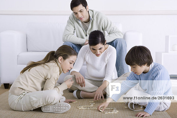 Familie verbringt Zeit miteinander  Mutter und Kinder spielen Domino  Vater schaut zu