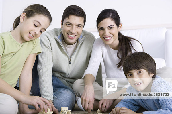 Familie spielt Dominosteine zusammen  lächelnd