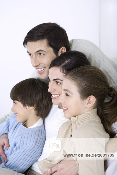 Man embracing his wife and children  all looking away and smiling