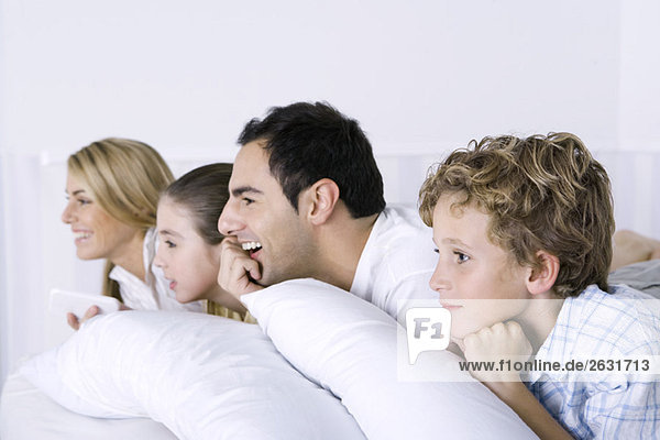 Family lying on bed  watching television  side view