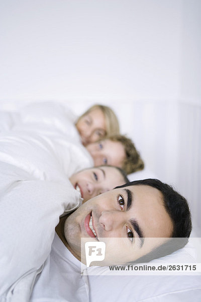 Man lying in bed with his family  smiling at camera