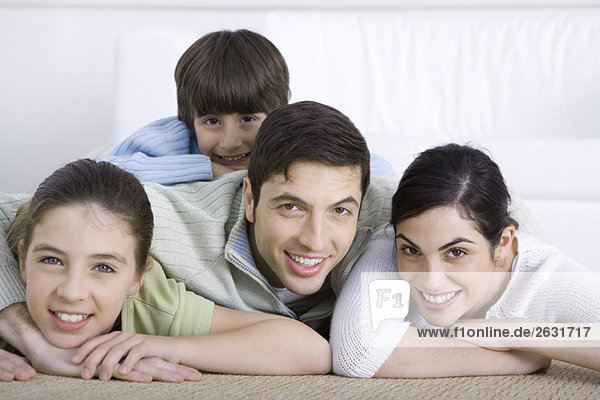 Portrait of smiling family lying together on floor  son lying on his father's back