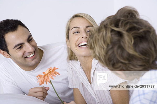 Frau lacht mit Ehemann und Sohn  hält Blume