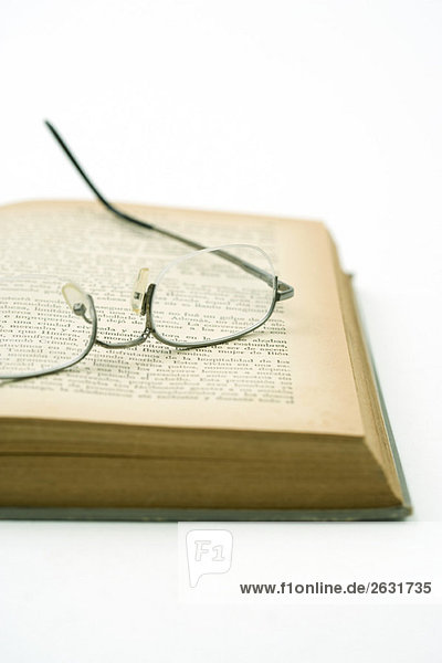 Brille auf vergilbter Seite des geöffneten Buches