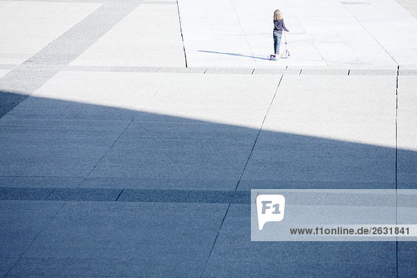 Kleinkind fahrender Roller allein auf dem öffentlichen Platz
