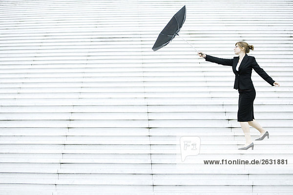 Geschäftsfrau kämpft mit Regenschirm im Wind