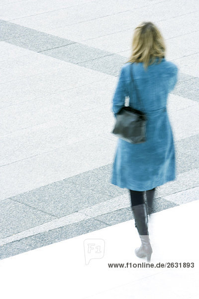 Frau in blauem Mantel absteigende Stufen im Freien