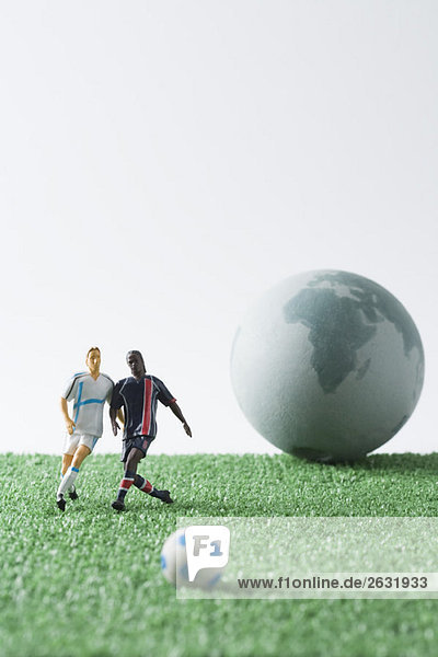 Miniatur-Fußballspieler jagen Fußball  Kugel im Hintergrund