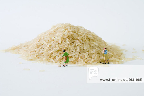 Miniatur-Frauen fegen großen Reishaufen