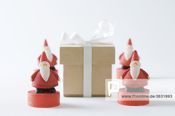 Weihnachtsmann-Figuren um das Weihnachtsgeschenk angeordnet