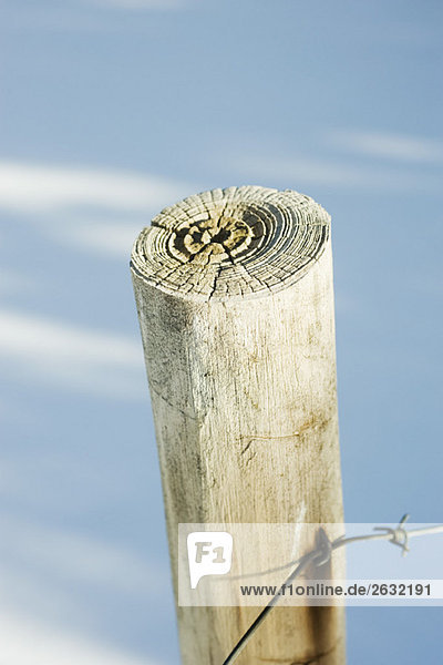 Wooden post with barbed wire  snow in background  close-up