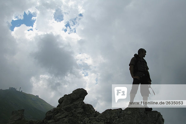 Man standing on hilltop with backpack