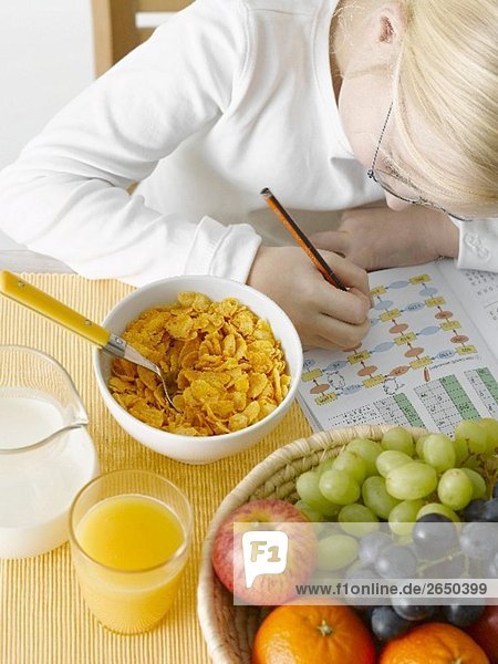 Mädchen mit Schulheft vor gesundem Frühstück