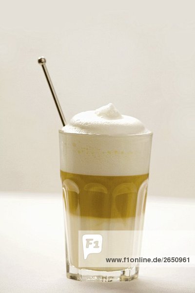 Ein Glas Latte Macchiato mit Kaffeelöffel