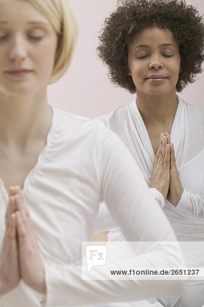 Two young women meditating with eyes closed