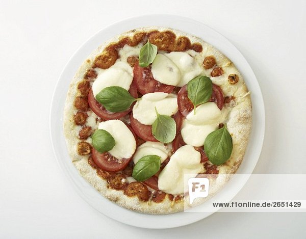 Eine Pizza mit Tomaten, Mozzarella und Basilikum