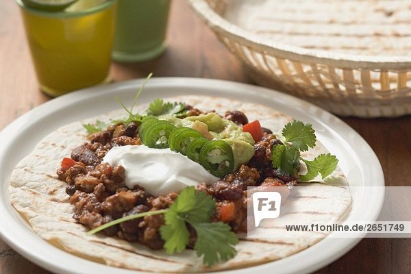 Mince and bean filling with sour cream on tortilla