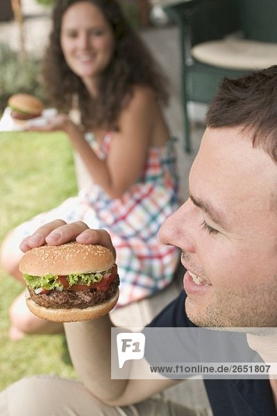 Paar isst Hamburger auf Terrasse