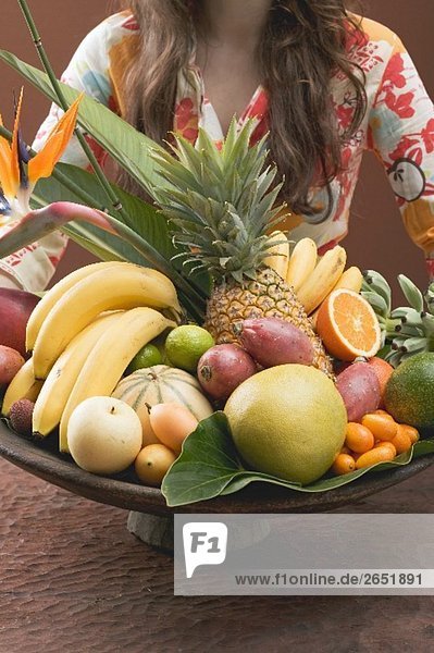 Frau hält Schale mit exotischen Früchten