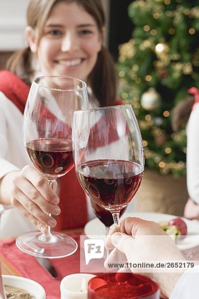 Young woman raising glass of red wine at Christmas dinner