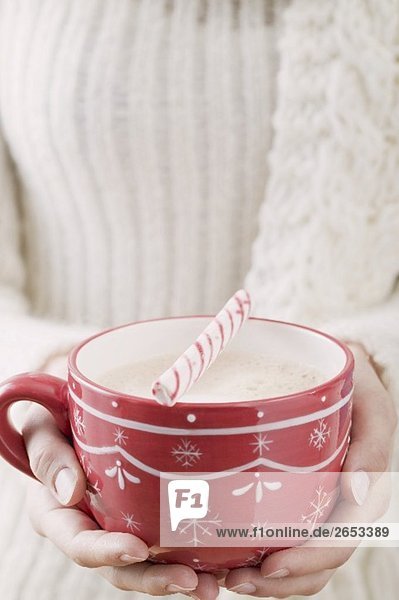 Woman holding cup of cocoa with candy cane (Christmas)