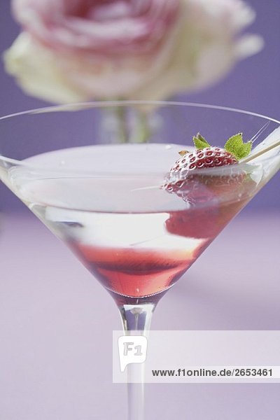 Martini mit Erdbeere im Glas  Rose im Hintergrund