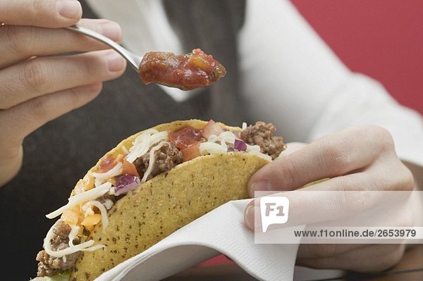 Frau gibt Sauce auf Taco mit Hackfleischfüllung