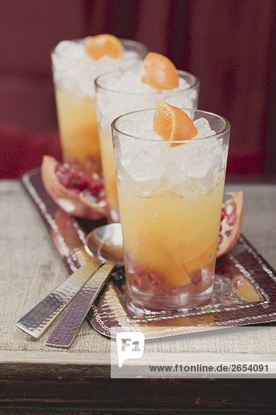 Drei fruchtige Drinks mit Orangen und Granatäpfeln