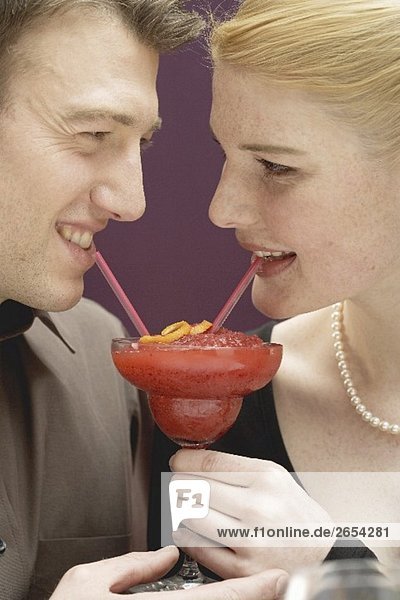 Romantisches Paar trinkt Strawberry Daiquiri aus einem Glas