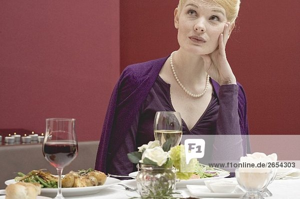 Gelangweilte Frau wartet auf den Partner beim Essen