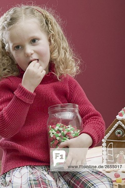 Kleines Mädchen nascht Candy Corn aus einem Vorratsglas