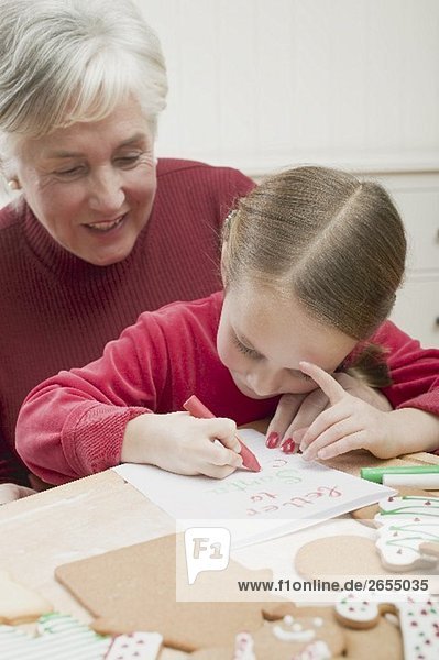 Small girl with grandmother writing Christmas letter