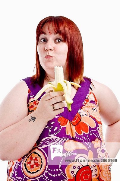 Übergewicht fat junge Frau tragen hell gefärbt Kleid essen eine Banane