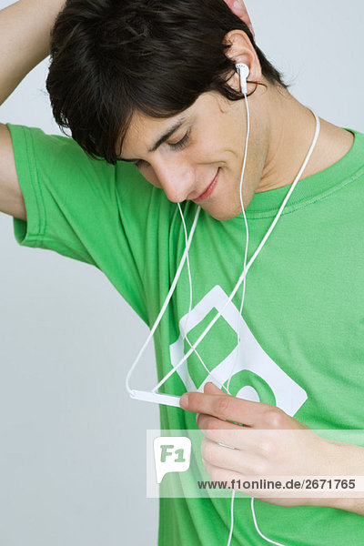 Junger Mann hört MP3-Player  lächelt  schaut nach unten