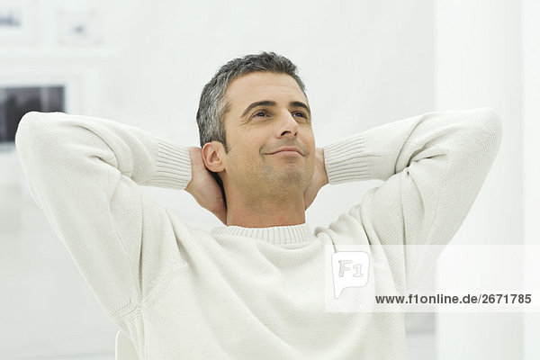 Man leaning back with hands behind head  smiling