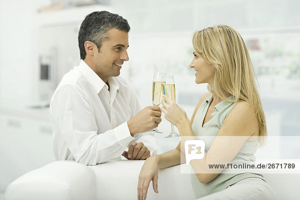 Couple clinking champagne glasses  smiling at each other