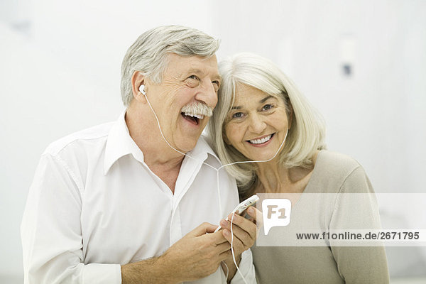 Seniorenpaar hört MP3-Player zusammen  Frau lächelt in die Kamera