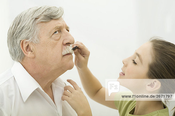 Großvater  der geduldig der Enkelin erlaubt  seinen Schnurrbart zu pflegen  Seitenansicht