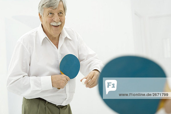Senior man playing table tennis  smiling