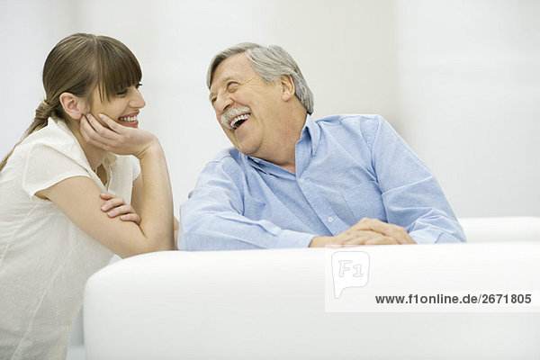 Älterer Mann und erwachsene Tochter lachen zusammen.