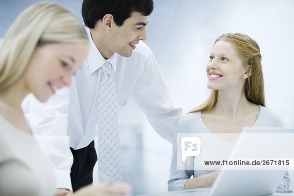 Businessman leaning over  chatting with female colleagues