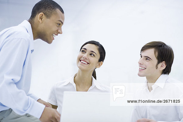 Young professionals smiling at each other  sitting near laptop