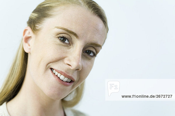 Woman smiling at camera  head tilted  portrait